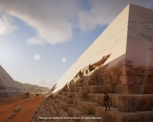 The side of an Egyptian Pyramid with a man standing at the base, as rendered in Assassin's Creed.