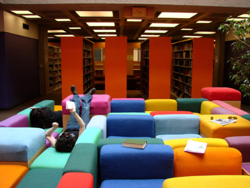 Student lounging on rainbow couches in Oberlin's Mudd library