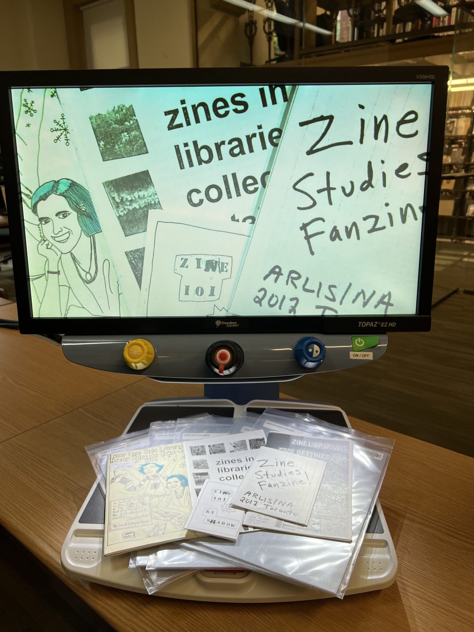 A CCTV reader with an array of zines on it's tray. These zines are all about librarianship.