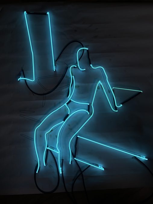 blue neon figure sitting on an edge